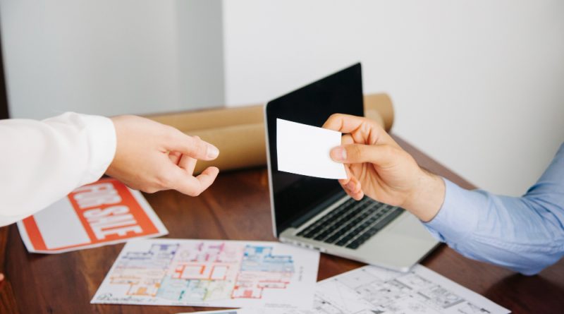 un agent immobilier tendant sa carte de visite à un client