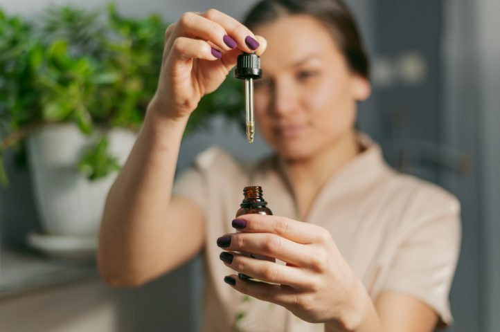 une femme versant des gouttes de CBD
