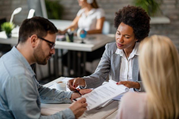 une femme fait remplir un contrat à un couple