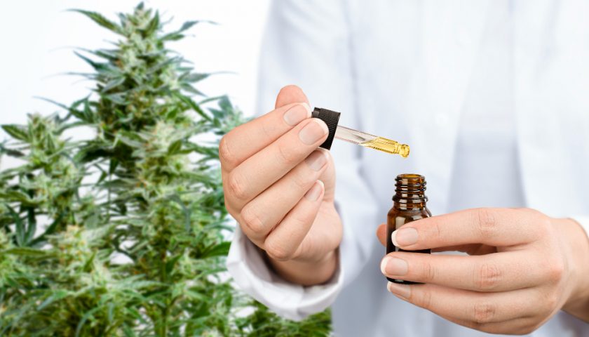 une personne en blouse blanche avec un flacon de CBD