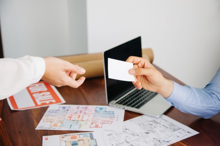 un agent immobilier tendant sa carte de visite à un client